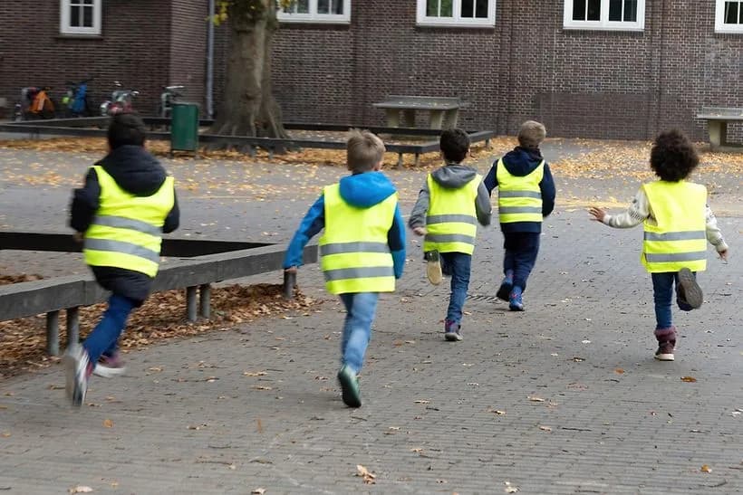 Fünf Kinder in gelben Warnwesten laufen über Schulhof, Grundschule/Kita Sicherheitsweste für Kinder beim Ausflug