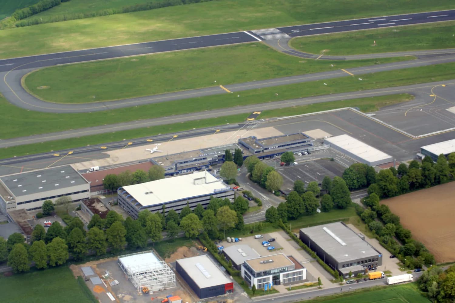 Luftaufnahme Flughafen Dortmund mit Start- und Landebahn, Vorfeld, Terminalgebäuden und abgestelltem Regionaljet, Parkplätzen und umliegenden Gewerbe- und Grünflächen