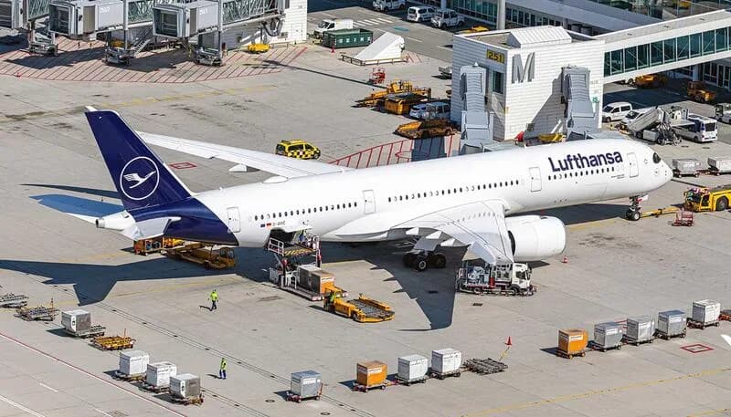 Lufthansa Passagierflugzeug am Gate beim Be- und Entladen von Gepäck und Fracht, Bodenabfertigung mit Fahrzeugen und Personal an Flughafenterminal