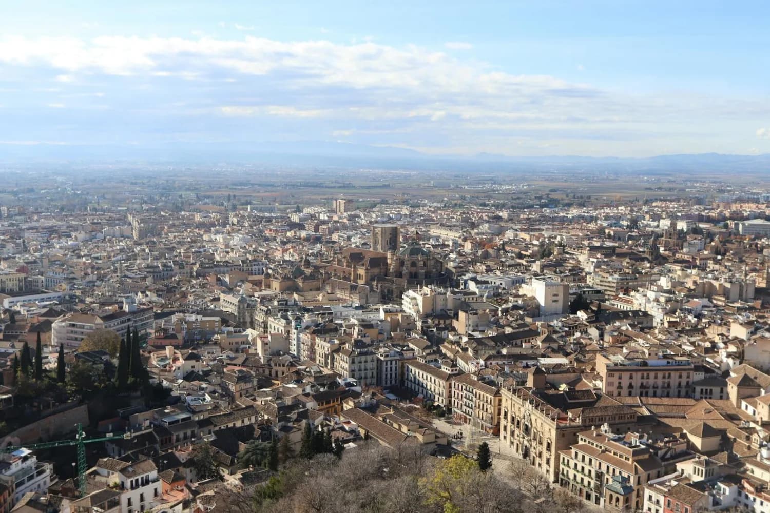 Panoramablick auf die Altstadt von Granada in Andalusien mit dicht bebauten Gassen, historischen Kirchen und umliegender Ebene