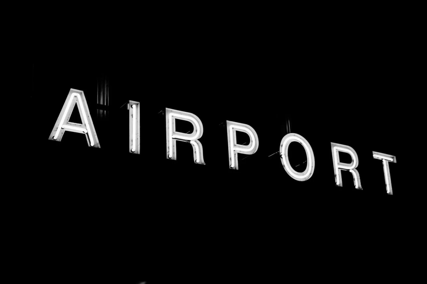 Leuchtendes Airport-Schild in Neon am Flughafen Zürich, schwarzweiß Szene bei Nacht