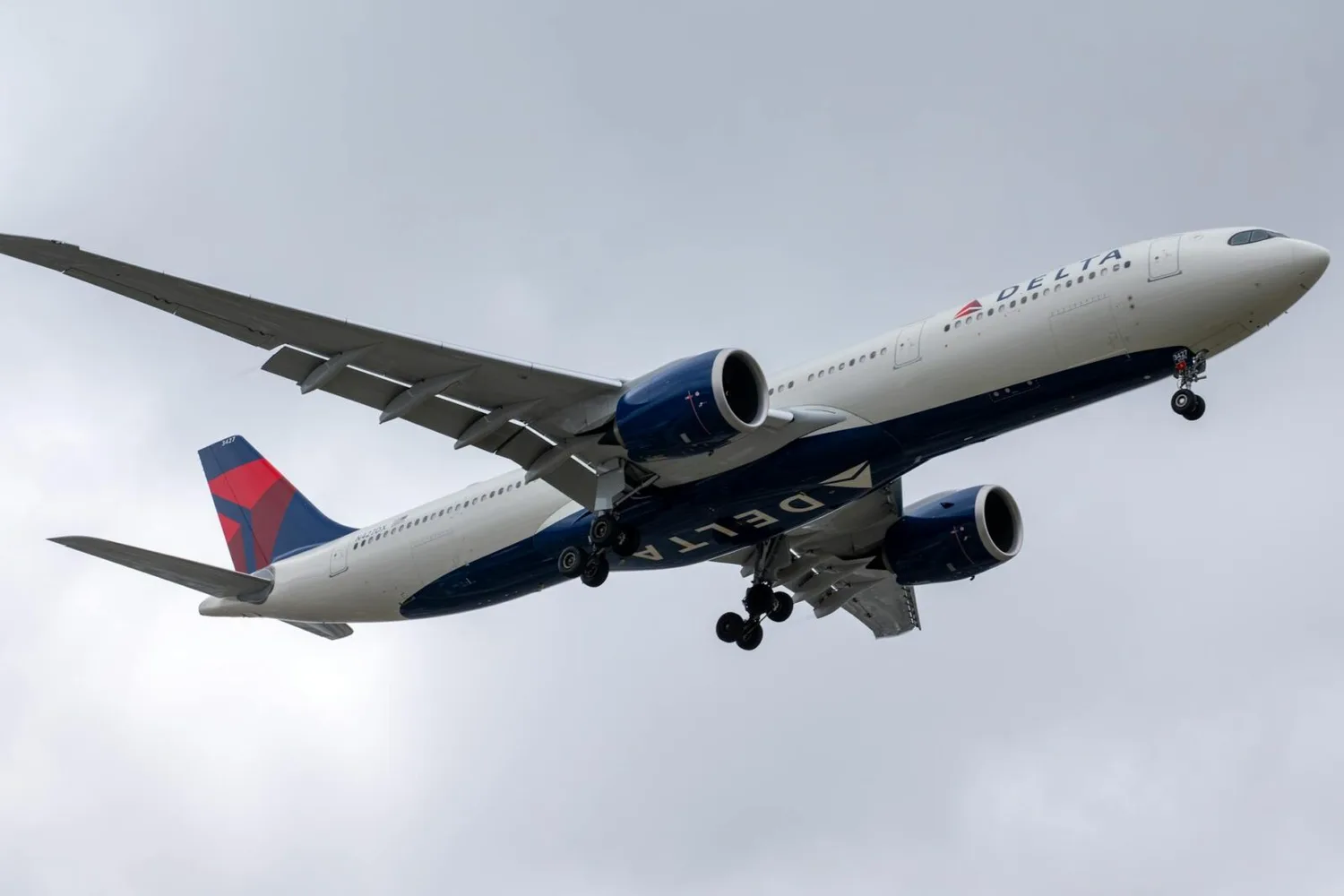 Delta Air Lines Passagierflugzeug Airbus im Landeanflug mit ausgefahrenem Fahrwerk vor bewölktem Himmel