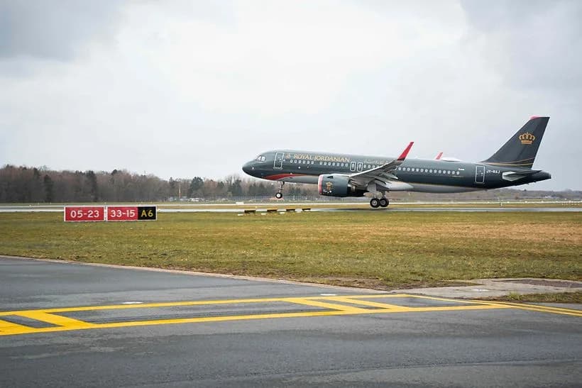 Royal Jordanian Passagierflugzeug beim Start über Graspiste am Flughafen, Flugzeug mit dunkler Lackierung und Königslogo auf dem Heck