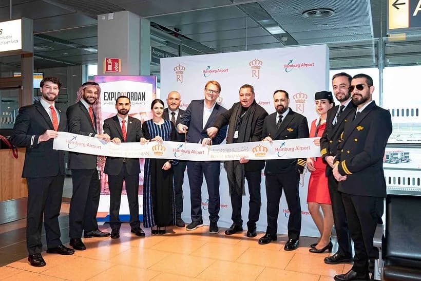 Royal Jordanian Crew und Flughafenpersonal schneiden Band bei Eröffnung am Hamburg Airport, Crewmitglieder in Uniformen posieren vor Eventwand