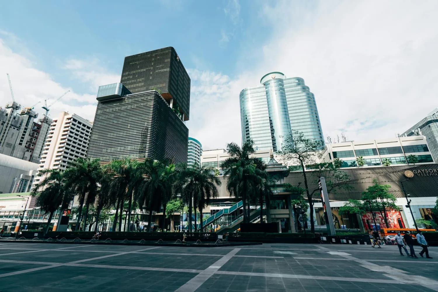 Skyline von Bangkok mit modernen Wolkenkratzern, Palmen und Fußgängerbereich vor Einkaufszentrum und Bürogebäuden