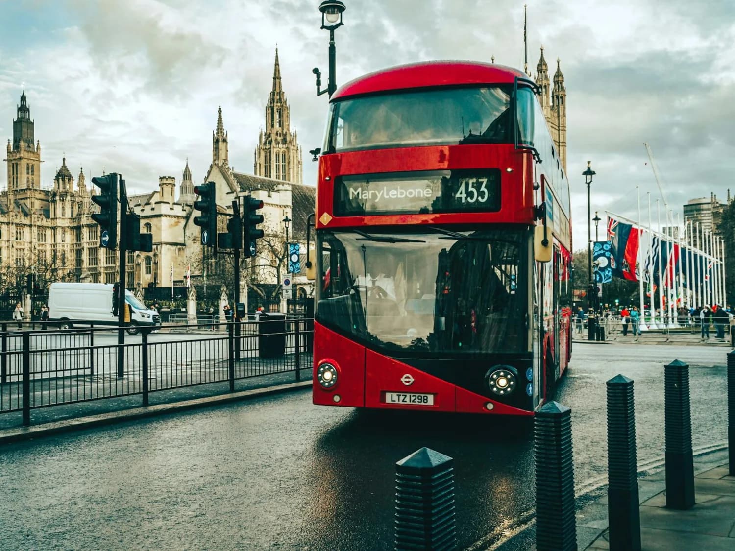 Roter Doppeldeckerbus vor dem Palace of Westminster in London, Straße mit Verkehrssignalen und Fußgängern