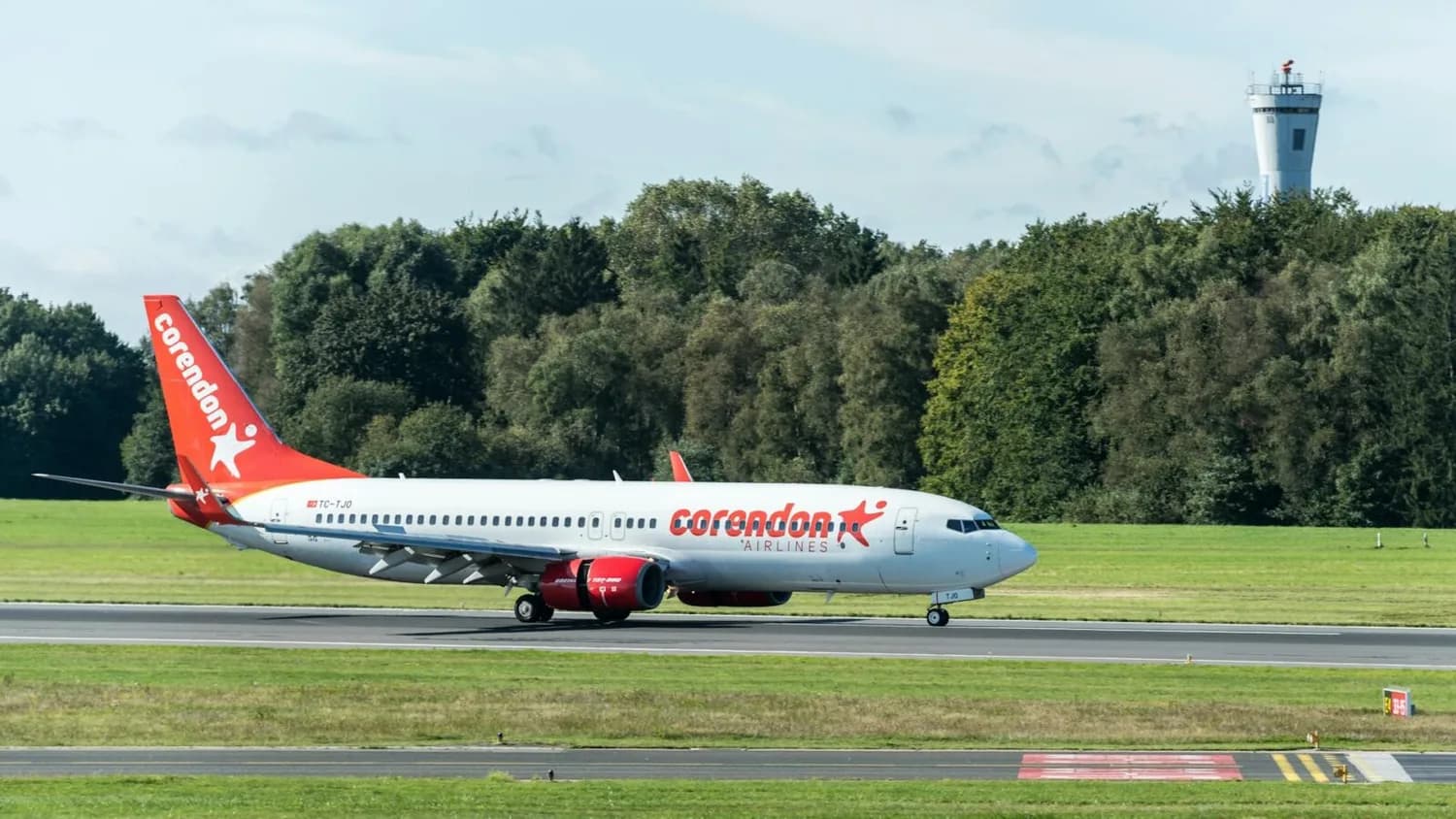 Corendon Airlines Boeing 737 auf Startbahn am Flughafen Nürnberg mit Kontrollturm und Baumbestand im Hintergrund
