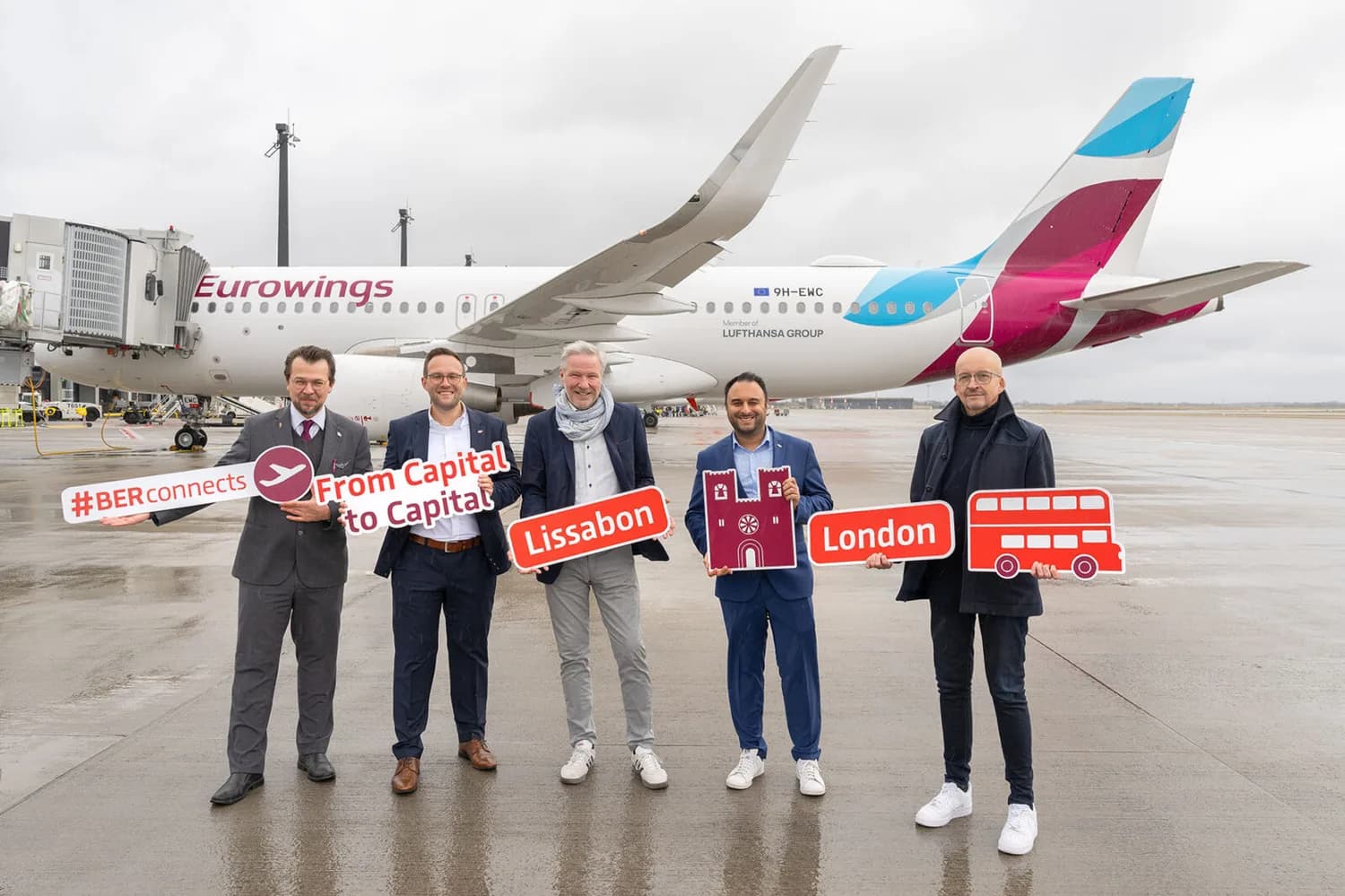 Fünf Vertreter vor Eurowings Passagierflugzeug am Flughafen mit Schildern für Lissabon und London, Werbefoto zur neuen Verbindung zwischen Hauptstädten (BER connects)