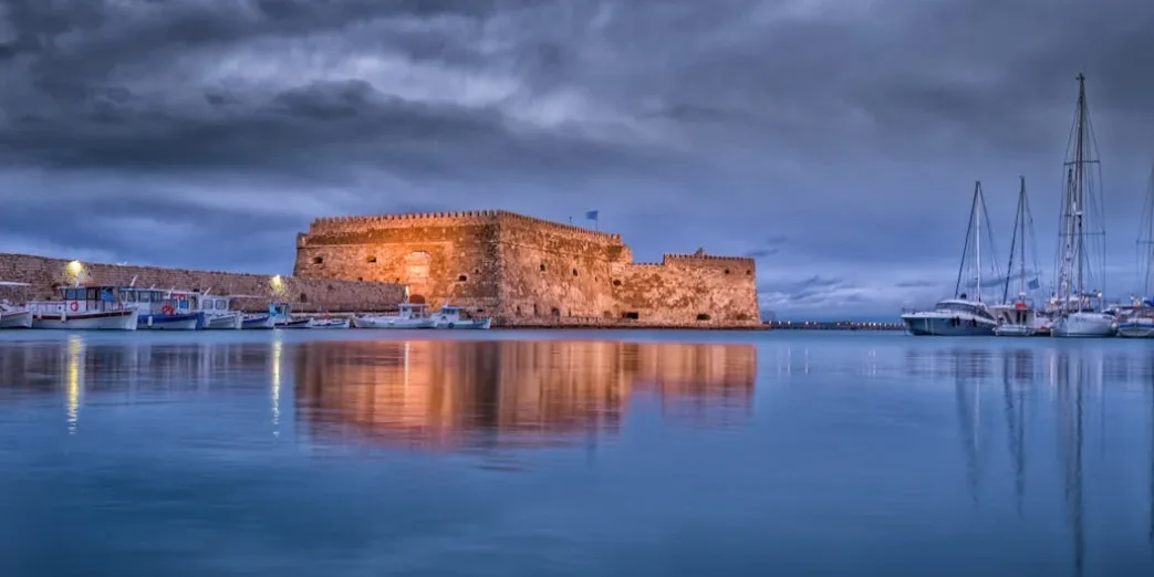 Koules-Festung am Hafen von Heraklion bei Abenddämmerung mit spiegelndem Wasser und angelegten Segelbooten
