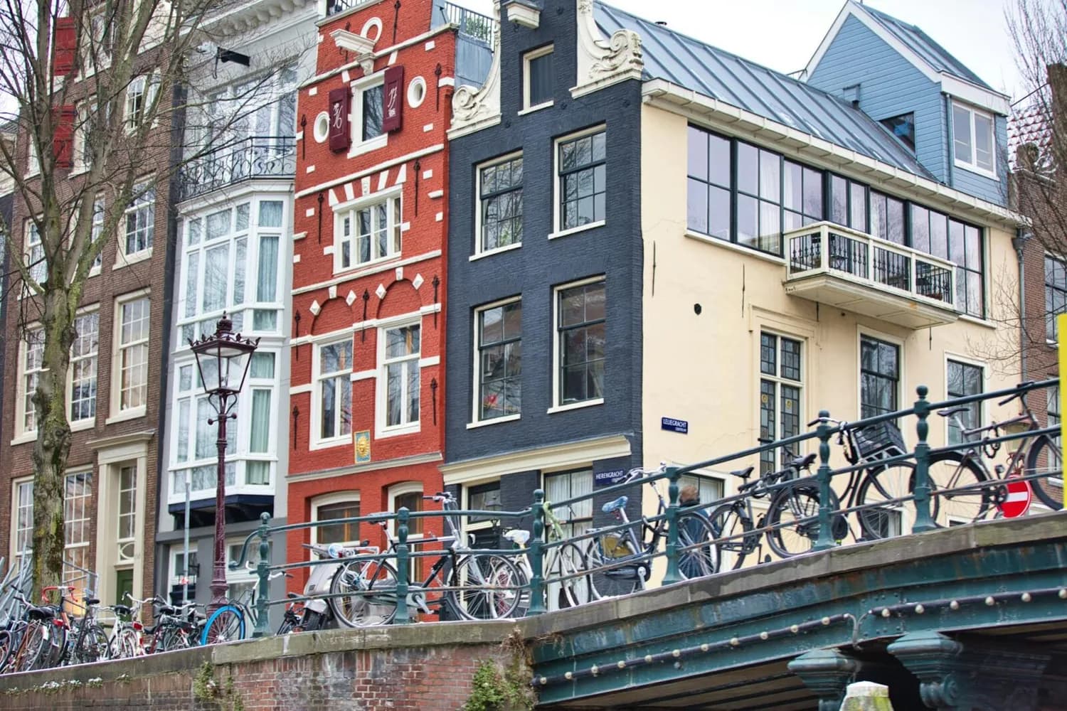 Historische Grachtenhäuser und Fahrräder an einer Brücke in Amsterdam, Innenstadtstraße Blick Richtung Nürnberg-Flugroute nicht sichtbar