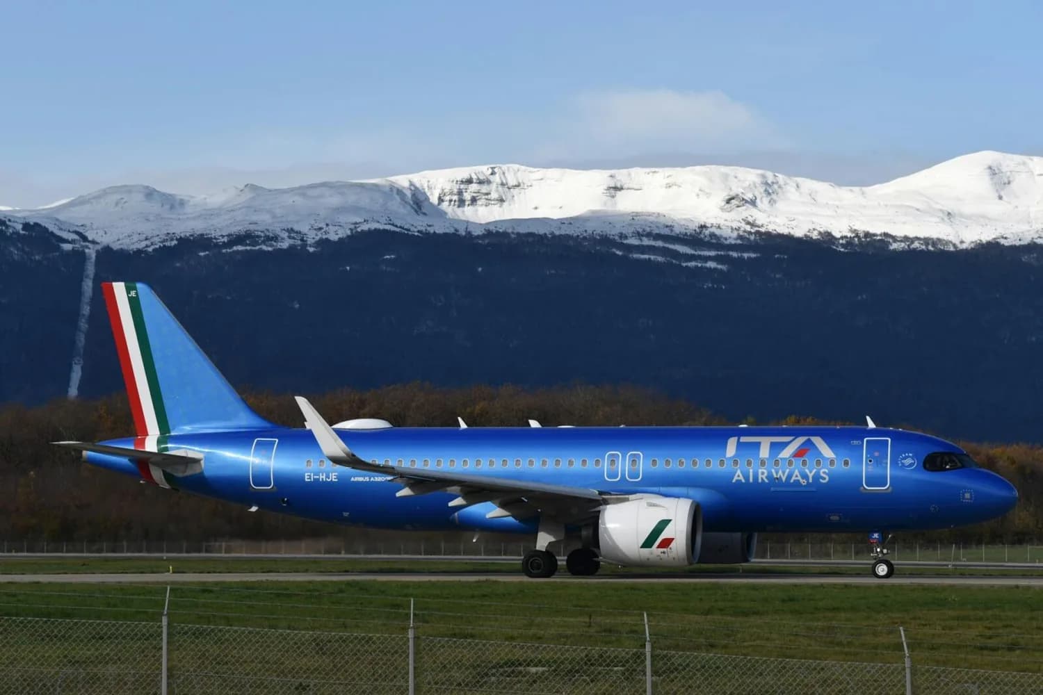 ITA Airways Airbus A320 in metallic Blau mit Tricolore-Heck beim Rollen vor schneebedeckten Bergen, Schwerpunkt Vielfliegerprogramm Miles und Airline-Branding