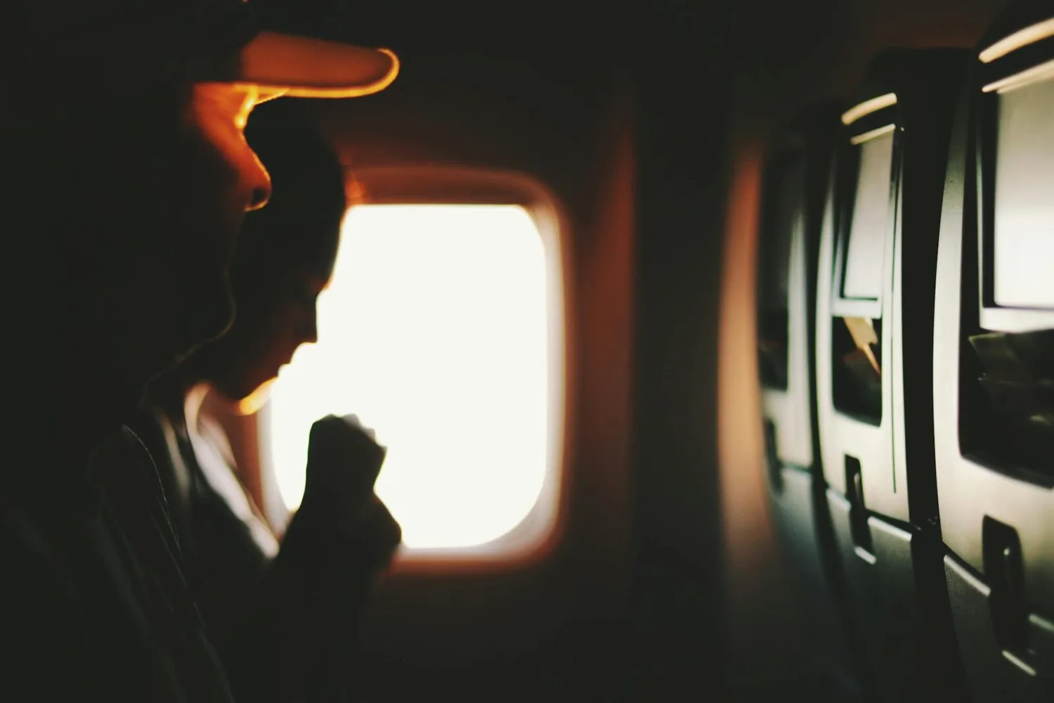 Schattenriss von Passagieren am Fensterplatz im Flugzeug mit In-Seat-Bildschirmen – symbolisch für Passagierrekord Flughafen Dortmund