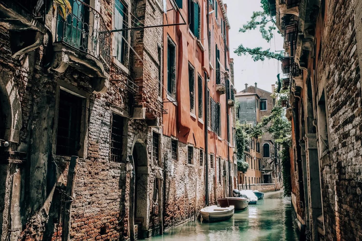 Venezianischer Kanal mit Booten zwischen alten Backstein- und Putzgebäuden, enge Gasse in Venedig, Szene geeignet für Flug von Venedig nach München Keywords: Venedig Kanal Boote historische Fassaden