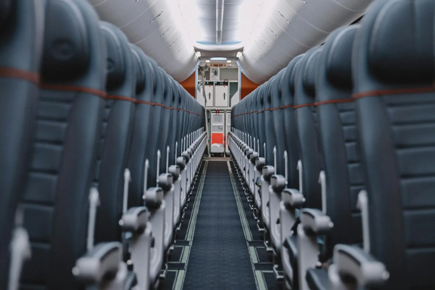 Leerer Passagiergang in Economy-Kabine einer Corendon Airlines Maschine ab Nürnberg, Reihen von grauen Sitzen und geöffnetes Servicefach am Heck