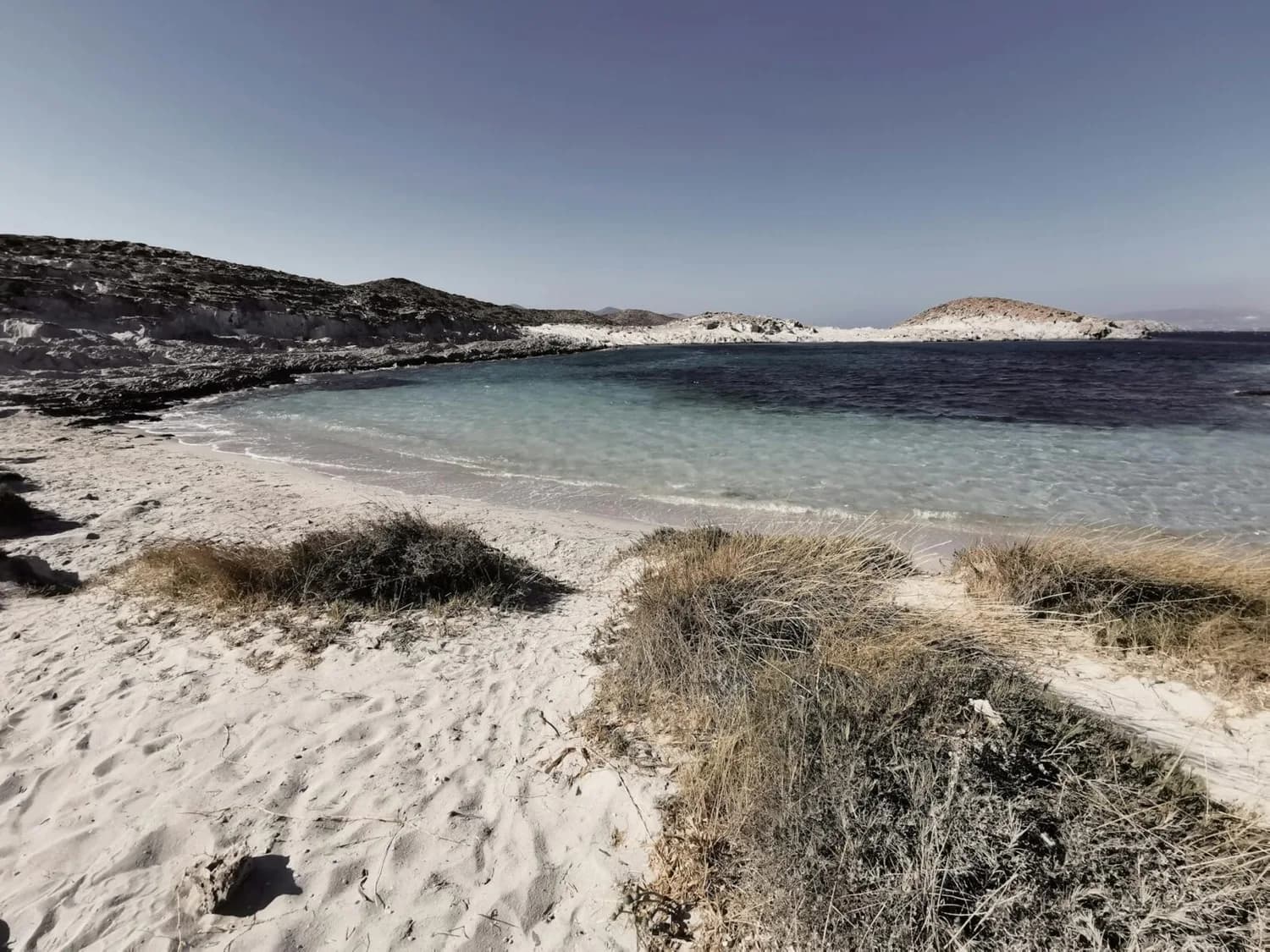 Sandstrand mit Dünenbewuchs und türkisblauem Wasser einer ruhigen Bucht auf griechischer Insel, ideales Parksleepfly-Ziel mit Eurowings/Aegean-Flugverbindungen