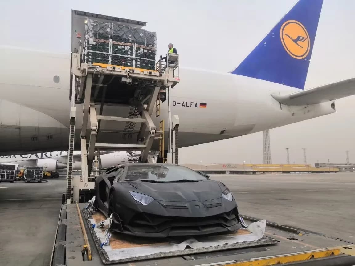 Lamborghini Aventador matte schwarz auf Ladeplattform vor Lufthansa Frachter beim Verladen am Flughafen