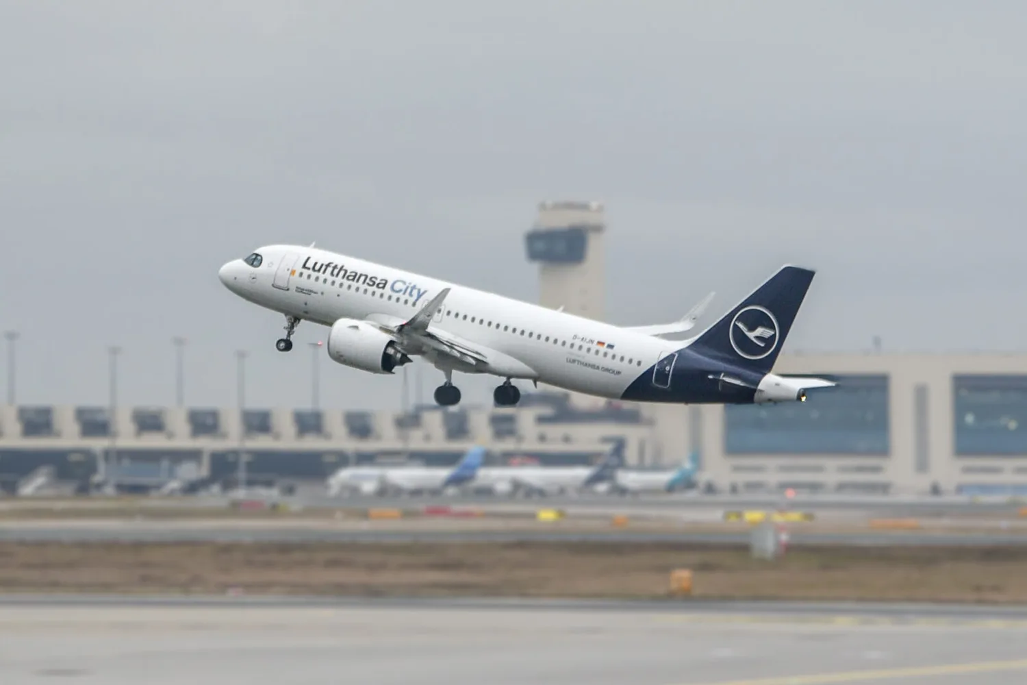 Lufthansa City Airbus A320 beim Start vor Terminal und Flugsicherungsturm am Flughafen