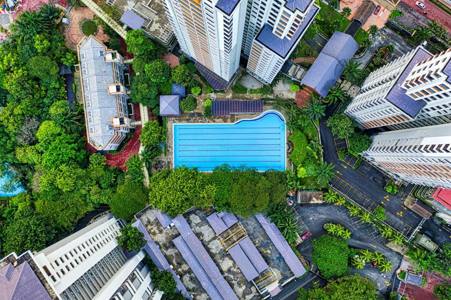 Luftaufnahme eines Wohnkomplexes in Kuala Lumpur mit blauem Außenpool, hohen Wohnhochhäusern und dichtem Grünflächenpanorama