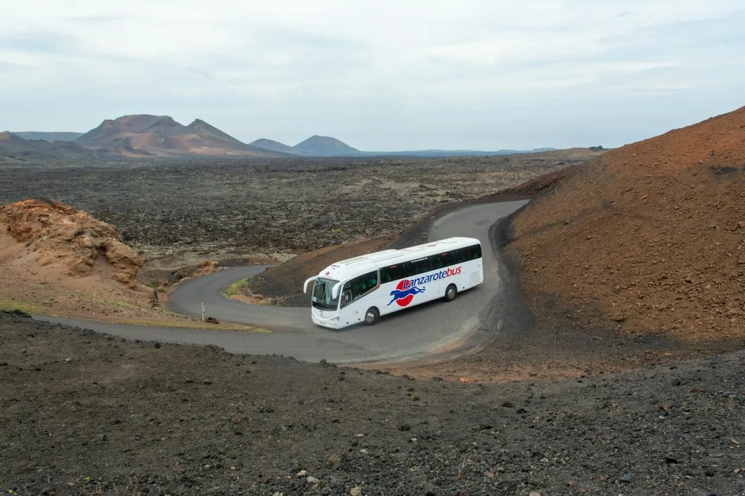 Touristenbus Lanzarotebus auf serpentinenreicher Straße durch vulkanische Mondlandschaft von Lanzarote, Busverbindung ab Flughafen Köln/Bonn