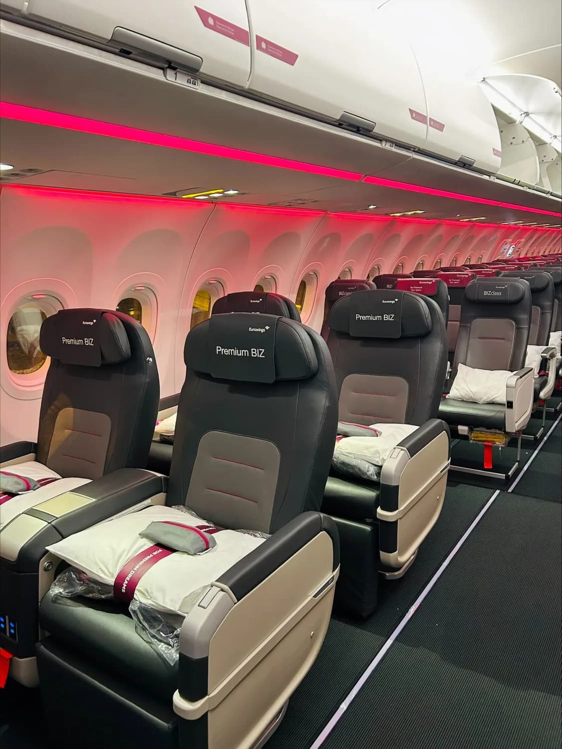 Eurowings Premium BIZ Sitze in Kabine bei Nachtbeleuchtung auf Erstflug BER–DXB, Reihen mit großen Ledersitzen, Kopfstützen mit Premium BIZ Beschriftung, Decken- und Fensterbeleuchtung