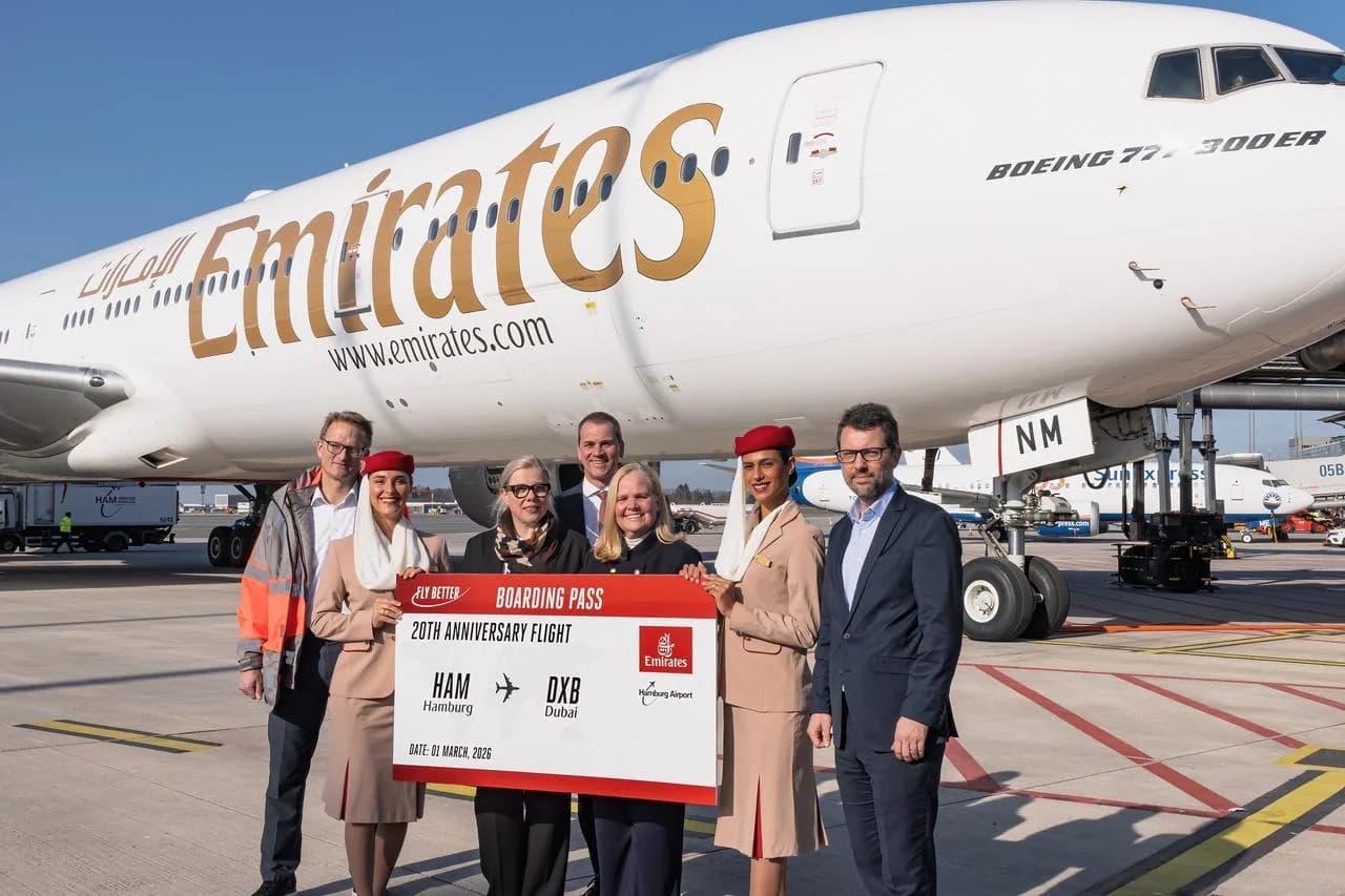 Emirates Boeing Flugzeug am Hamburger Flughafen mit Crew und Gästen, symbolische Boarding-Pass-Tafel zum Jubiläumsflug Hamburg–Dubai, Stewardessen in Uniform vor Flugzeugrumpf