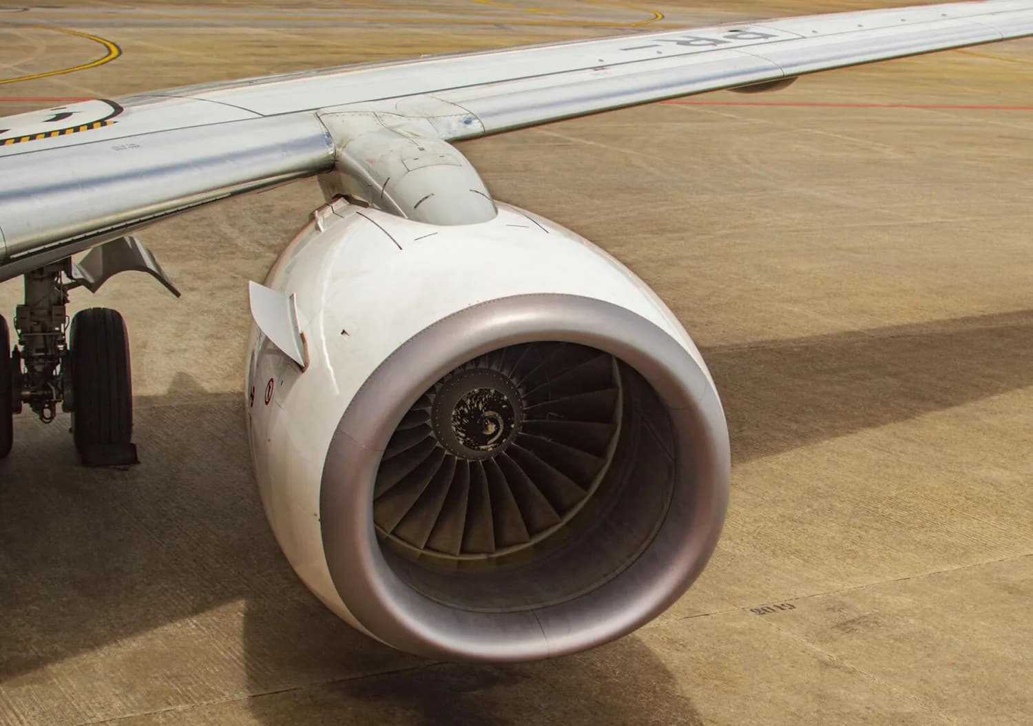 Triebwerk und Flügel einer Verkehrsmaschine am Boden, Fokus auf Turbineneinlass und Hinweis auf grünen Flugkraftstoff ESAF