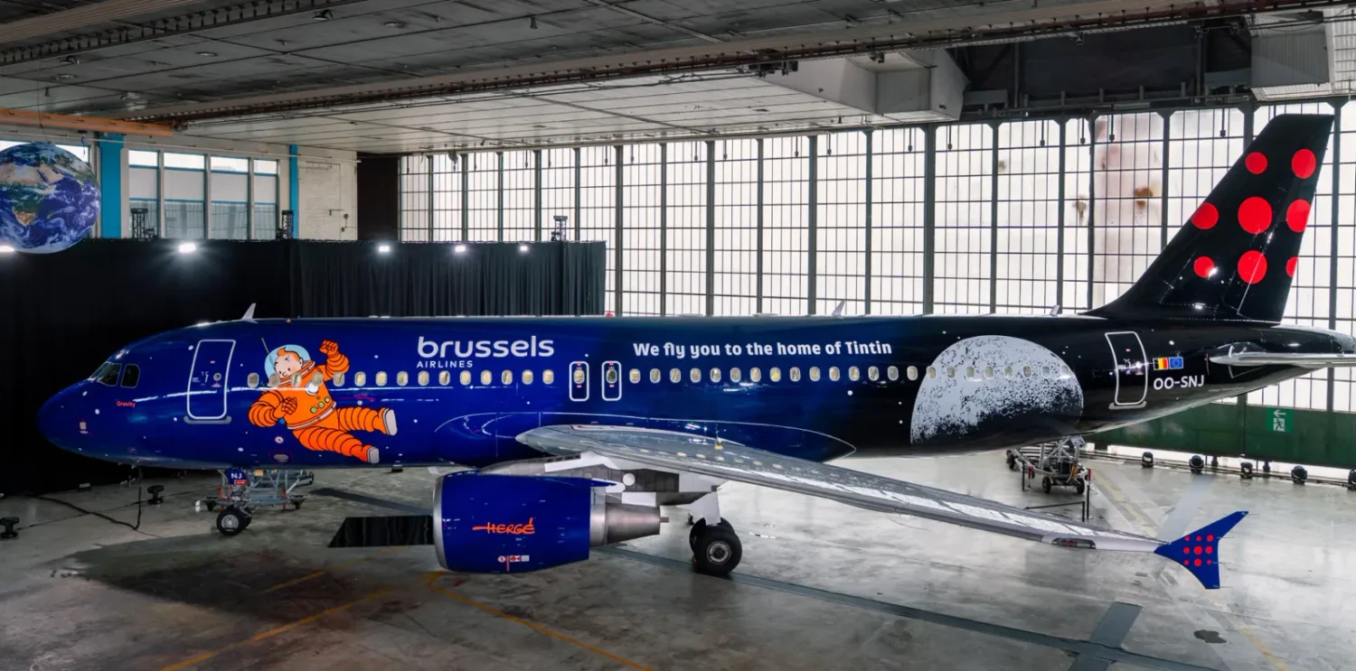 Brussels Airlines Flugzeug mit dunkelblauer Tintin-Weltraum-Bemalung, Astronauten-Tintin-Motiv, Mondgrafik auf Rumpf und Airline-Logo in Hangar - © Brussels Airlines / Hergé / Tintinimaginatio 2026