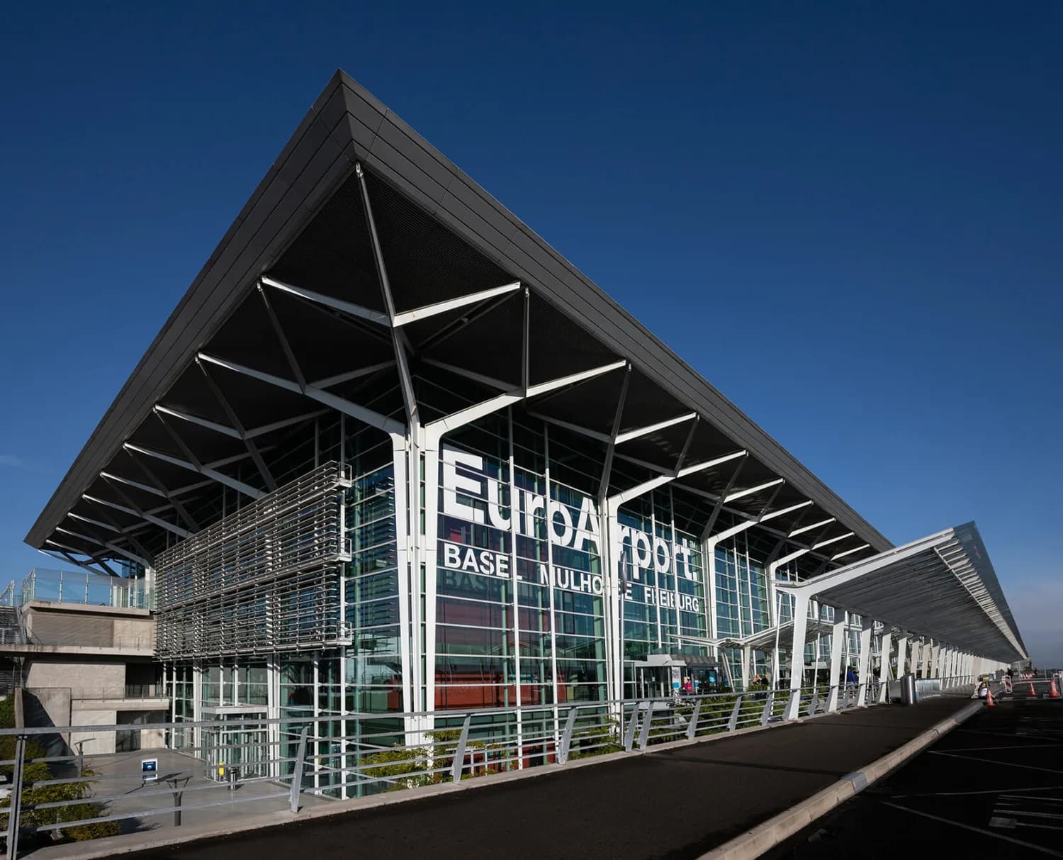 EuroAirport Terminal 2 Glasfassade und markante Vordachkonstruktion am Passagierbereich mit sichtbarem EuroAirport-Logo und Einfahrtsbereich. © EuroAirport