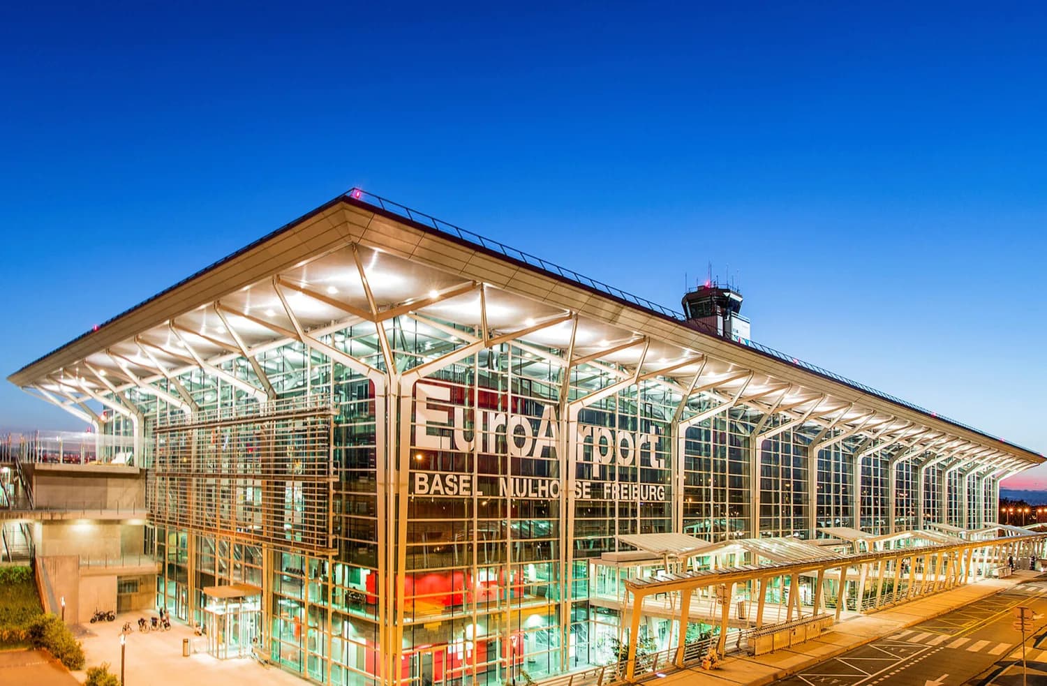 EuroAirport Terminal 3 Glasfassade mit beleuchtetem Vorfeld und Kontrollturm bei Abenddämmerung - © EuroAirport