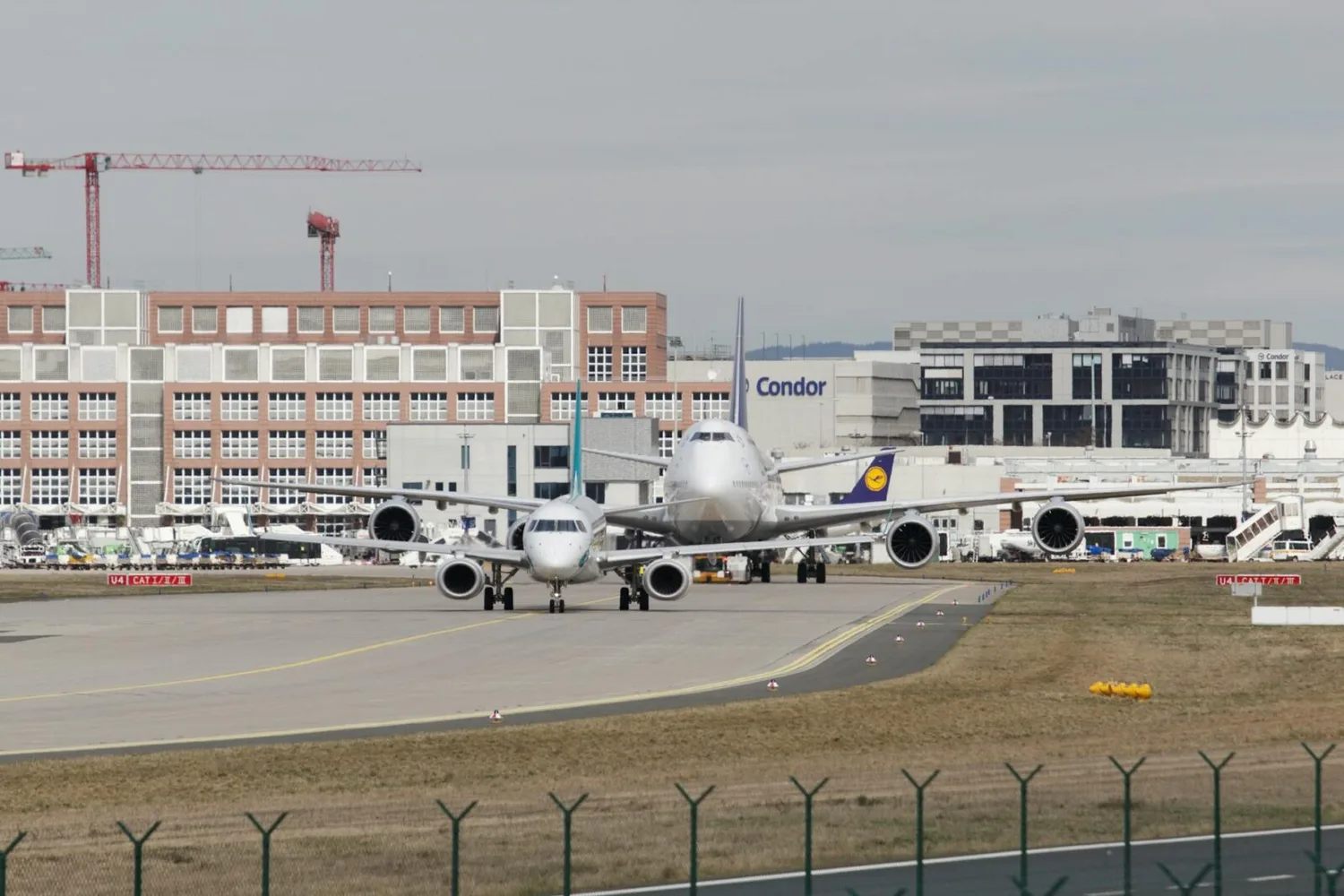 Zwei Flugzeuge auf Taxiway am Flughafen Frankfurt mit Lufthansa Jumbo und Terminalgebäuden im Hintergrund, Fraport Verkehrsaufkommen im Januar