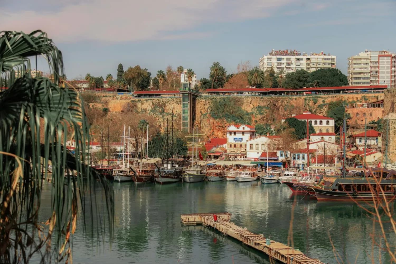 Hafen von Antalya mit Holzsteg, geparkten Ausflugsbooten und Felsklippe im Hintergrund – Gewinnspiel-Motiv für Freebird Türkei-Reise