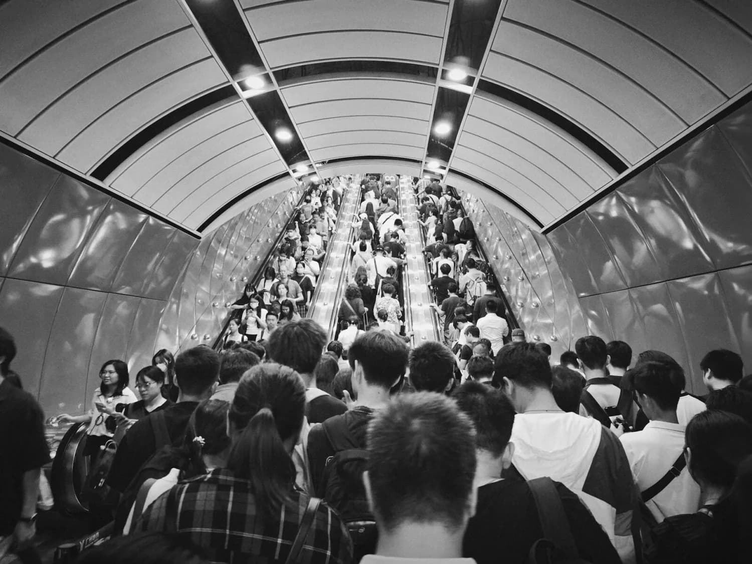 Menschenmenge auf rolltreppe in U‑Bahnstation, dichter Pendlerstrom und lange Wartezeiten non‑Schengen Bereich