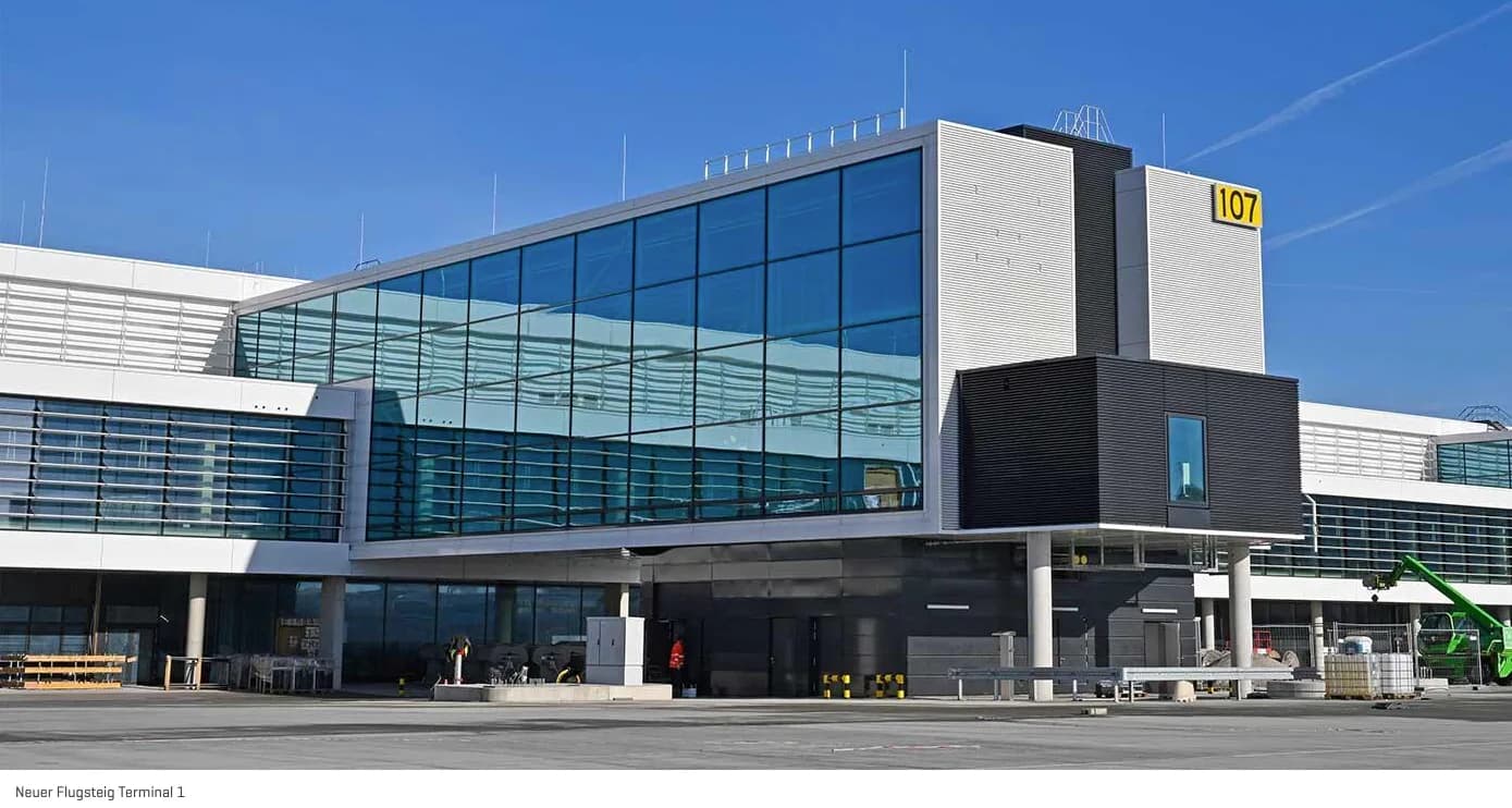 Moderner neuer Flugsteig am Flughafen München Terminal 1 mit großflächigen Glasfassaden, Gangbrücke und Vorfeldbereich