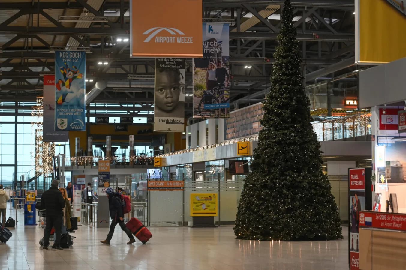 Terminalbereich von Airport Weeze mit Passagieren, großen Werbebannern und dekoriertem Weihnachtsbaum