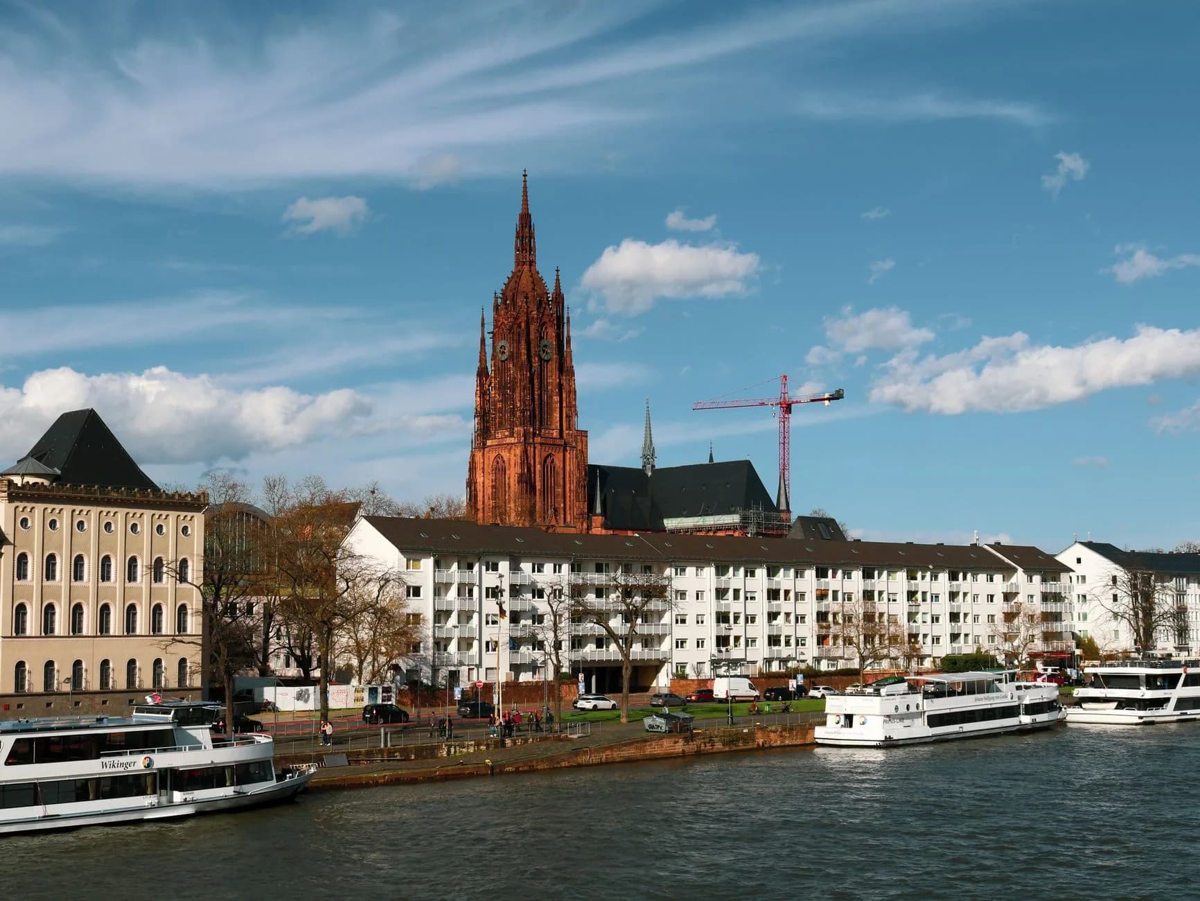 Frankfurter Dom überragt die Mainufer-Bebauung, davor liegen Ausflugsschiffe am Kai