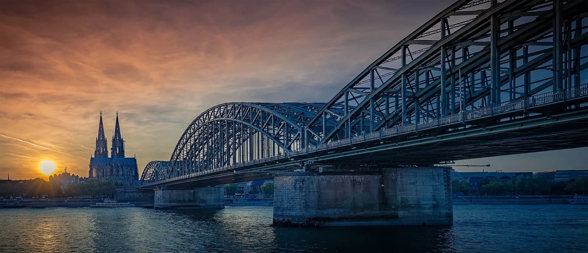 Hohenzollernbrücke über dem Rhein mit Kölner Dom im Hintergrund bei Sonnenuntergang