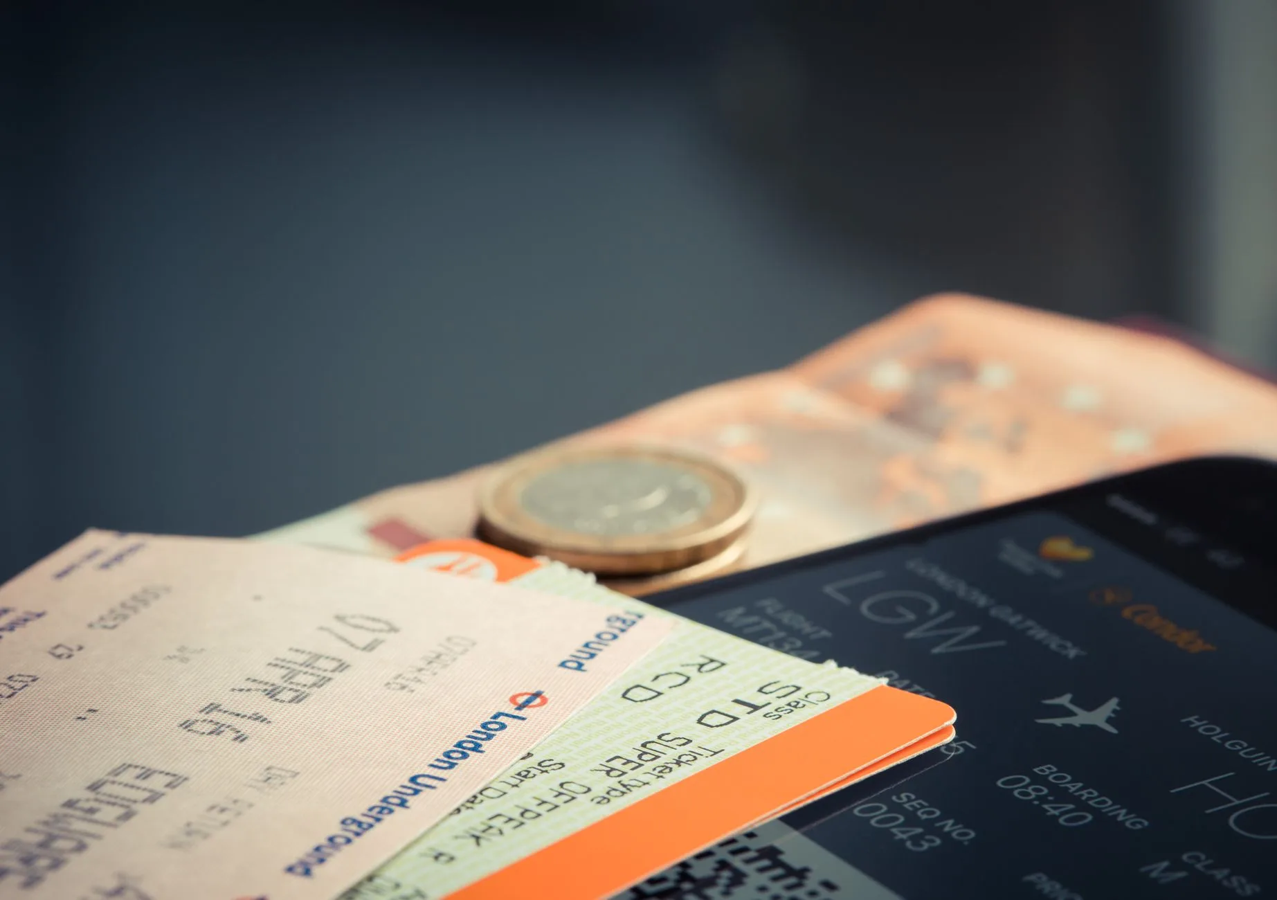 Fahrkarten der London Underground und ein Flugticket mit Smartphone-Bordkarte für Flug nach London Gatwick liegen übereinander