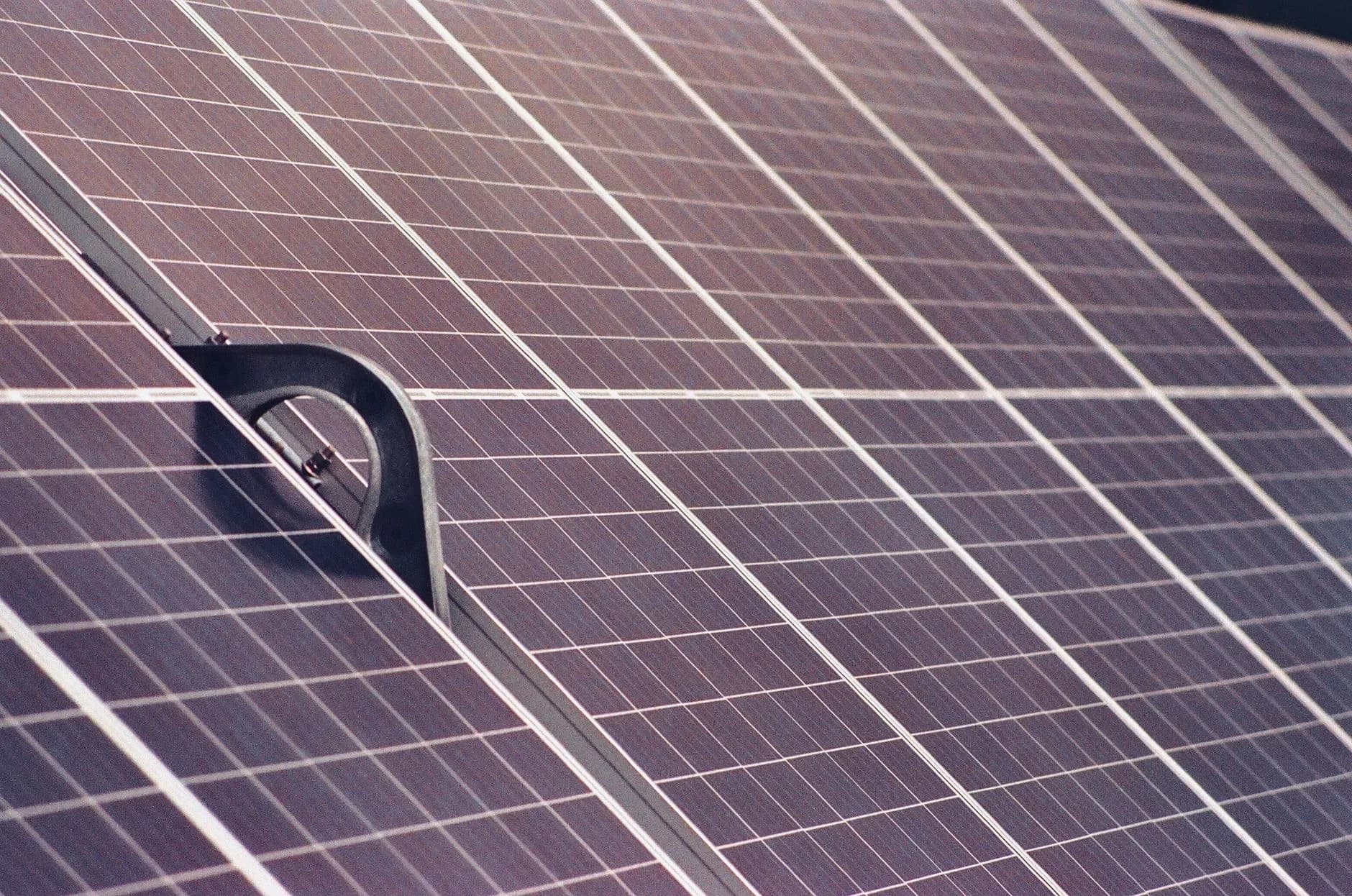 Nahaufnahme von Solarpanels auf einem Dach mit schwarzer Halterung im Vordergrund