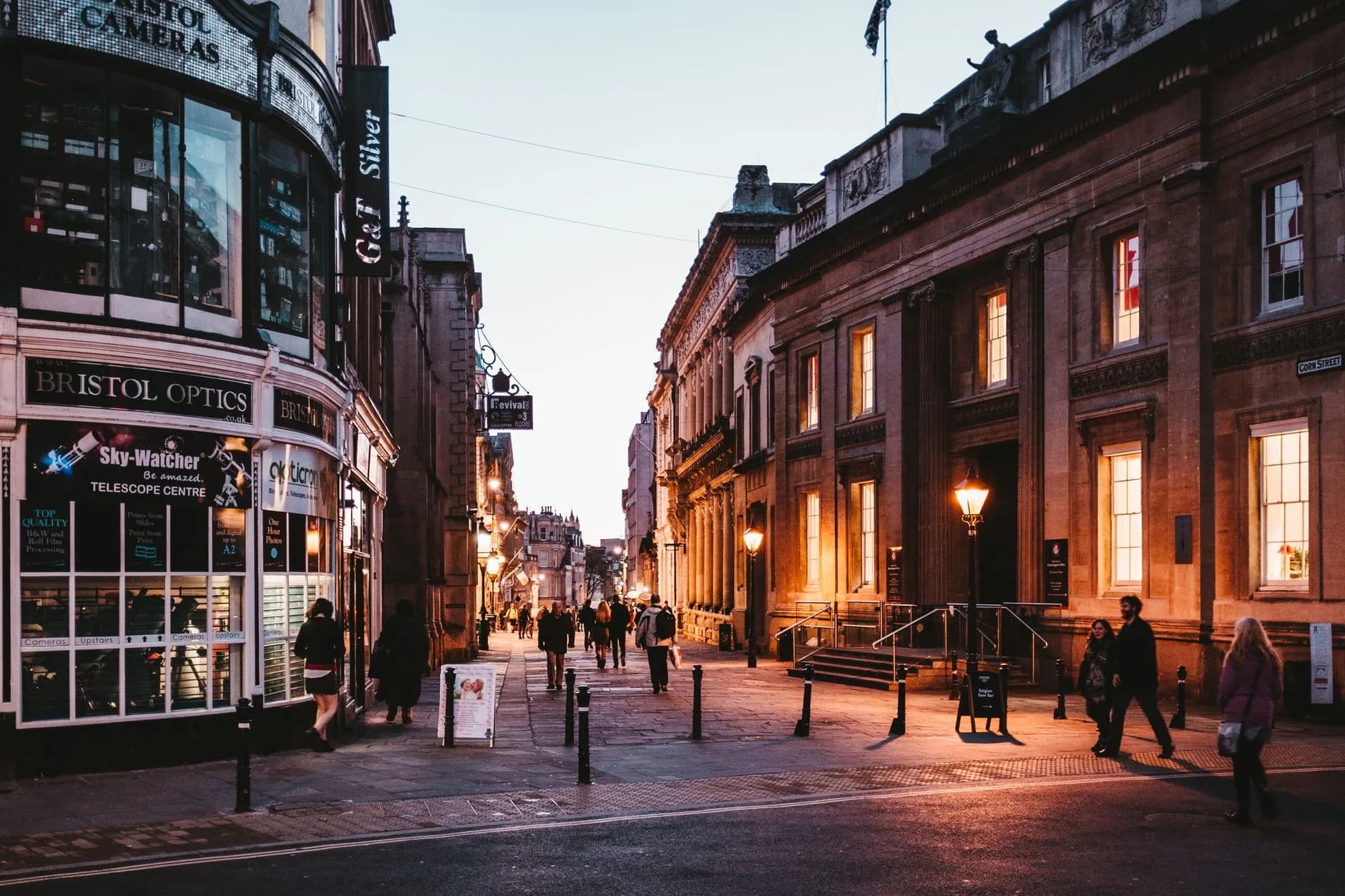 Historische Einkaufsstraße in Bristol mit beleuchteten Fassaden und Fußgängern in der Abenddämmerung