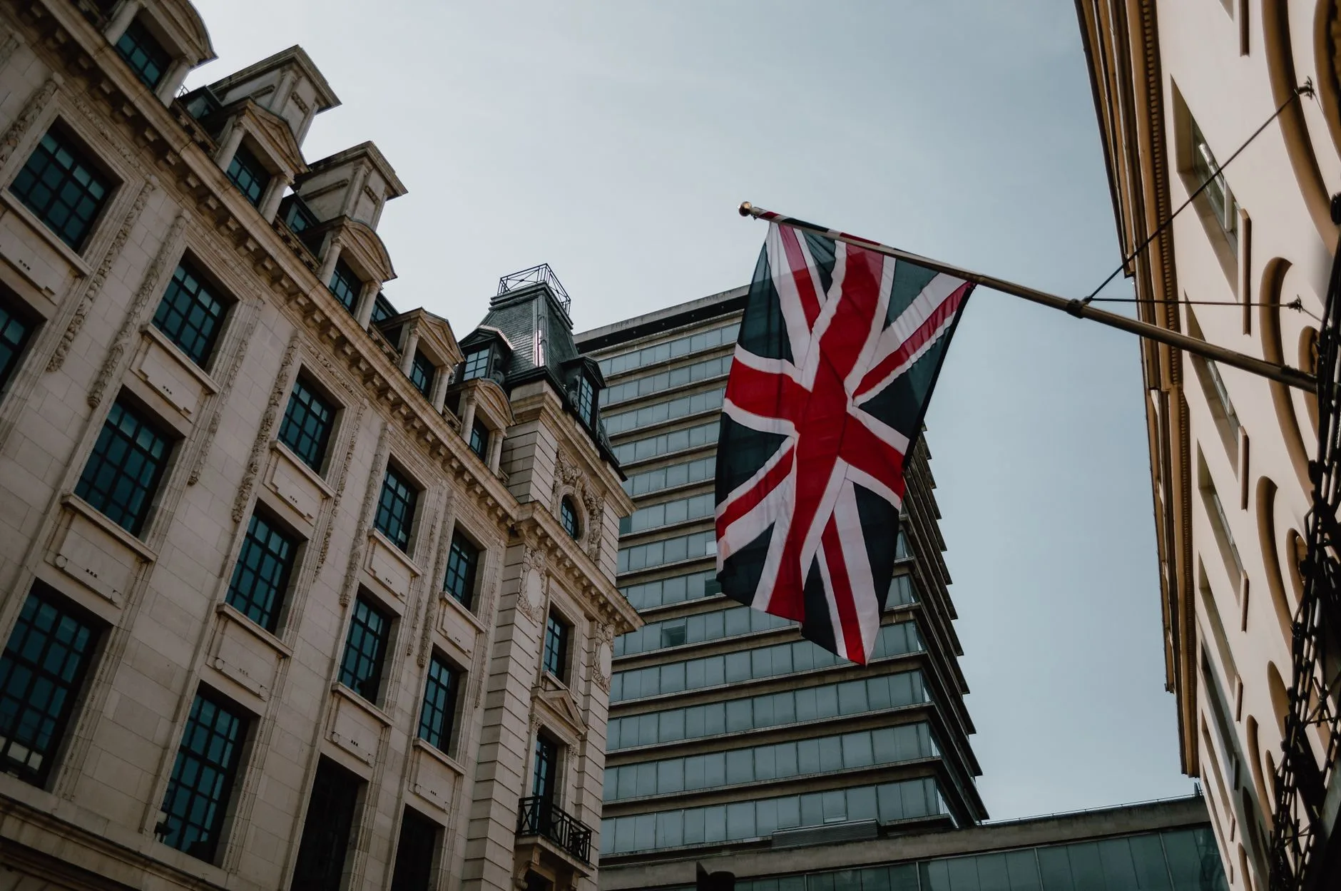 Union Jack an einer Fahnenstange zwischen historischen Fassaden und einem Hochhaus in London