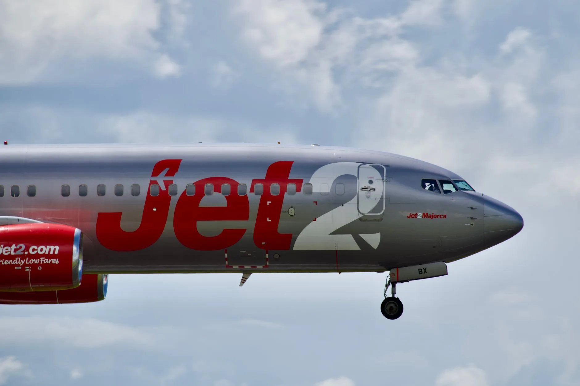Flugzeug von Jet2 mit ausgefahrenem Fahrwerk im Steigflug vor bewölktem Himmel