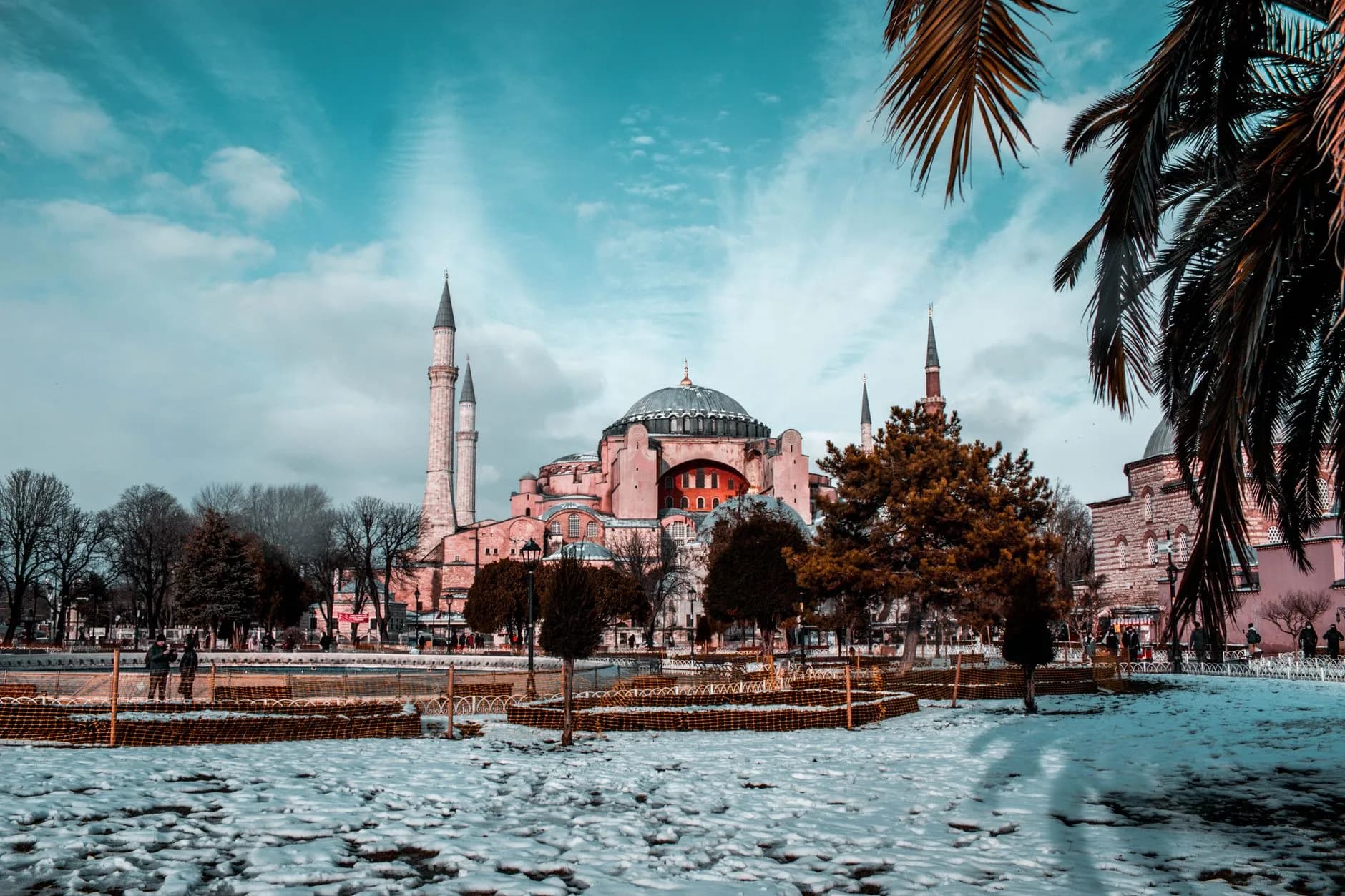 Hagia Sophia in Istanbul mit Minaretten und Kuppel, umgeben von schneebedecktem Park und Palmenzweigen im Vordergrund