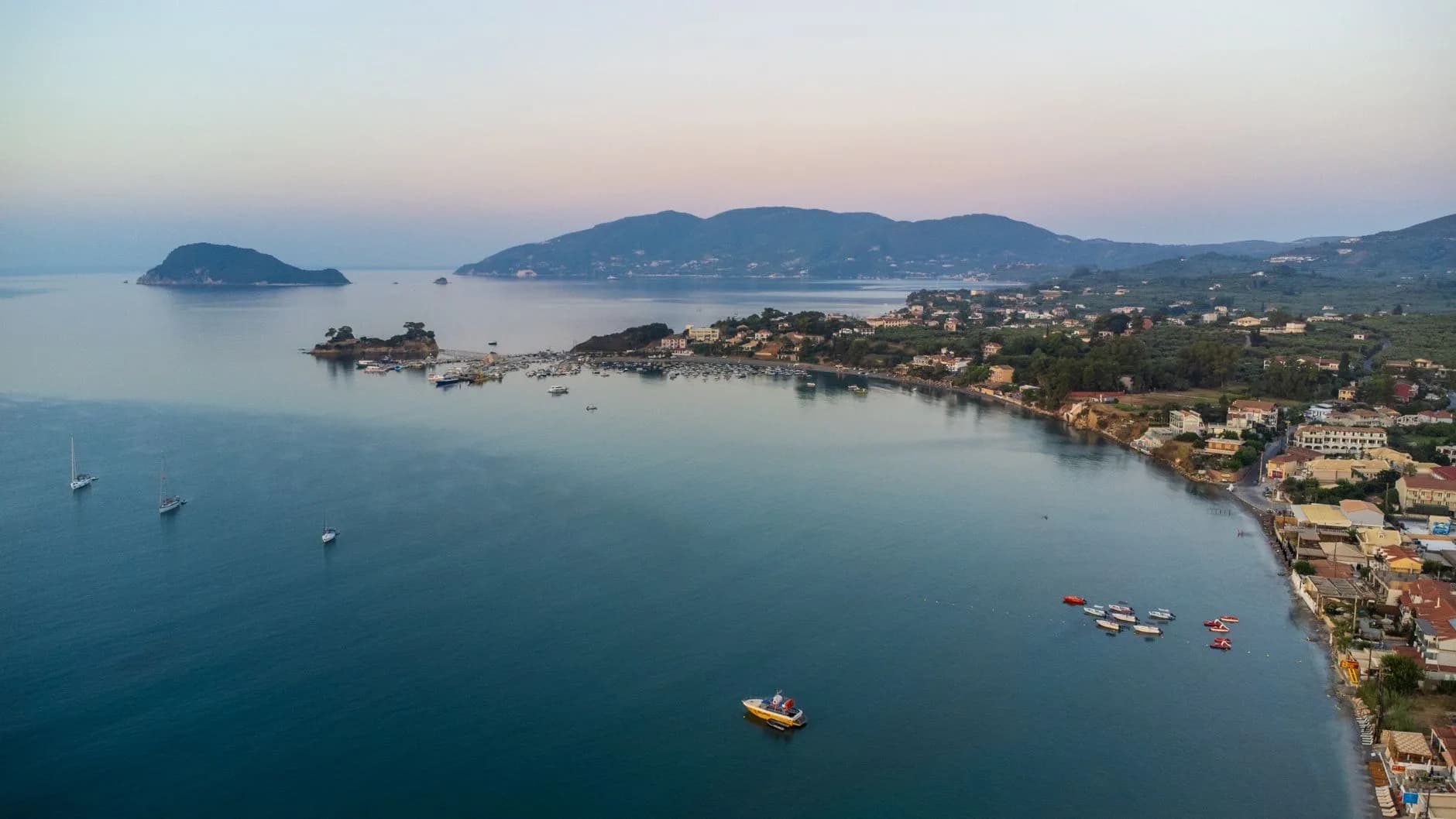 A tranquil aerial view of a coastal town by the Mediterranean sea at sunrise, showcasing a serene bay.