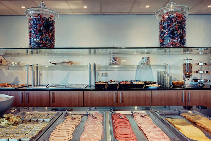 Buffet mit Aufschnitt, Käsescheiben, Schalen und zwei großen Glasbehältern mit Süßigkeiten oben.