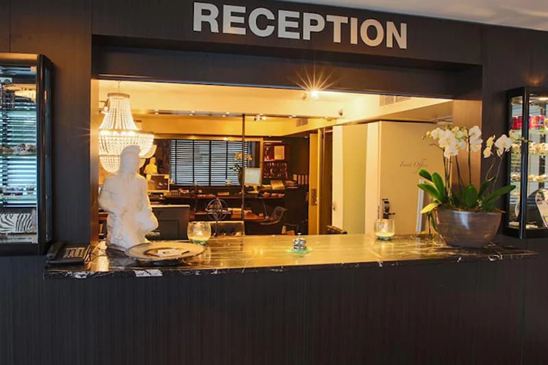Rezeptionstresen mit Marmortheke, Orchideen, Figur und beleuchtetem Schild RECEPTION.