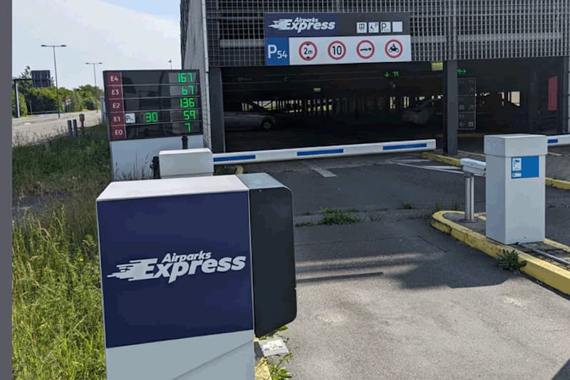 Einfahrt zum Parkhaus P54 mit Schranke, Airparks Express Säule und Anzeigetafel für freie Stellplätze.