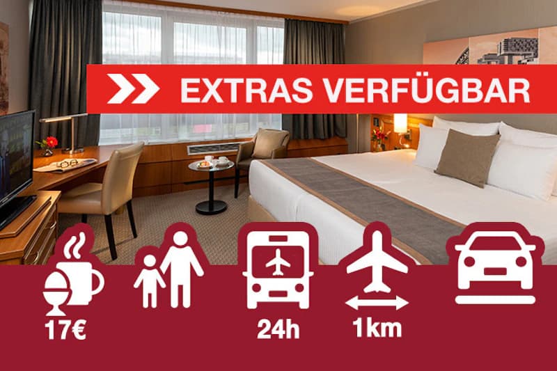 Großes Hotelzimmer mit Doppelbett, Schreibtisch, Sesseln und großem Fenster; rotes Banner Extras verfügbar und Serviceicons am Bildrand.