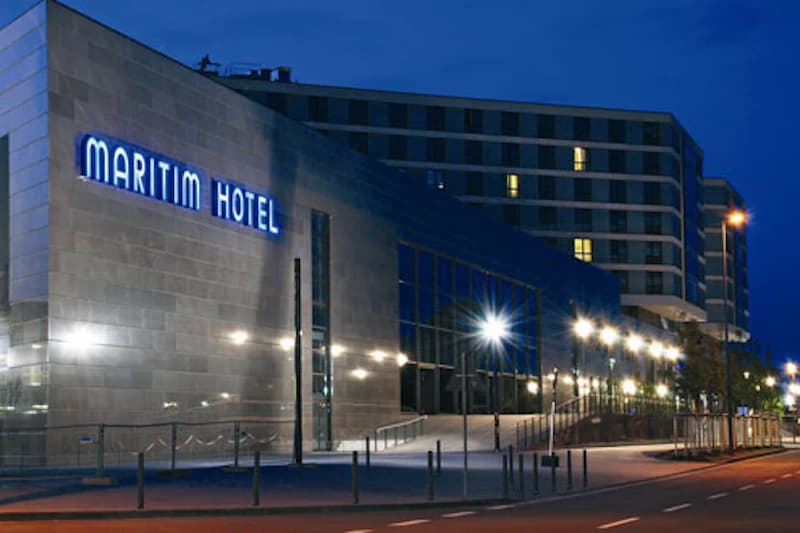 Außenfassade des Maritim Hotels am Abend mit beleuchtetem Schriftzug und Gehweglampen.