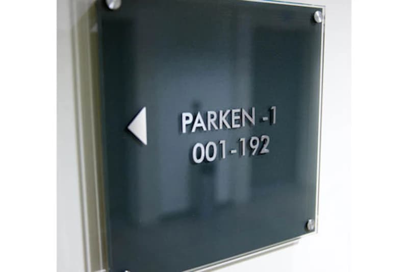 Dunkles Wandschild mit Pfeil und Schrift PARKEN -1 001-192.