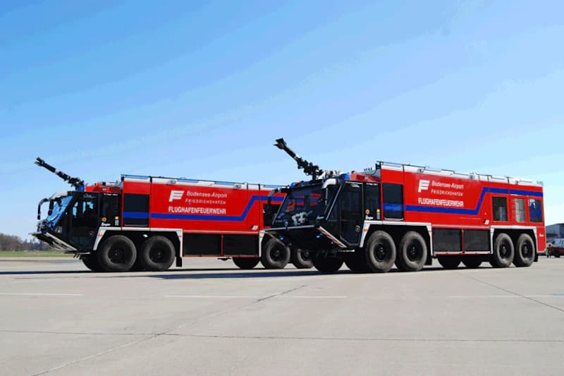 Zwei rote Flughafenlöschfahrzeuge mit Beschriftung Bodensee-Airport Friedrichshafen auf dem Rollfeld.